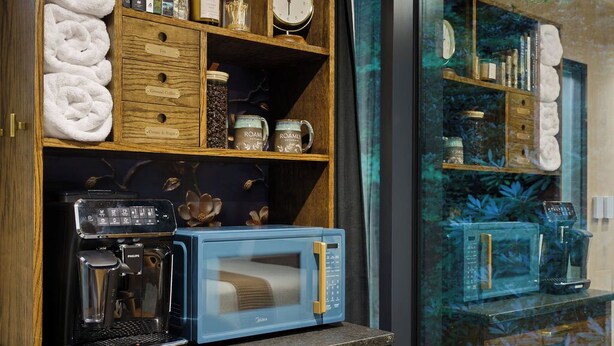 A kitchenette with a coffee maker, microwave, and storage shelves. - Mirror house wellness retreat: private sauna, hot tub, spring-fed cold plunge & your own waterfall. Tucked on 35 acres along the French Broad River, minutes from Brevard breweries, Pisgah & DuPont. (Pisgah Forest)
