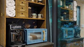 Une petite cuisine équipée d’une machine à café, d’un four à micro-ondes et d’étagères de rangement.