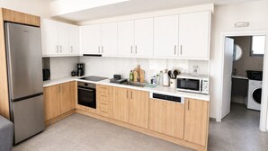 A modern kitchen with white cabinets, a stainless steel refrigerator, a microwave, and a dishwasher. - Zidros Apartments Maisonette Apartment 3 (Sfakaki)