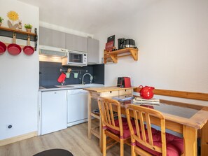 A compact kitchen with a microwave, sink, and wooden cabinets. - Studio with a balcony and a view of the mountains (Saint-Sorlin-d´Arves)