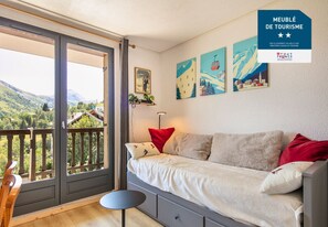 A cozy room with a bed, a small table, and a balcony with a scenic view. - Studio with a balcony and a view of the mountains (Saint-Sorlin-d´Arves)