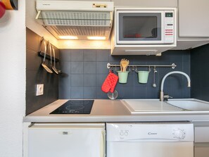 Une petite cuisine équipée d’un four à micro-ondes, d’une cuisinière, d’un évier et d’un petit réfrigérateur.