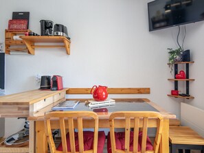 A compact living space with a wooden dining table, a red kettle, and a coffee machine. - Studio with a balcony and a view of the mountains (Saint-Sorlin-d´Arves)