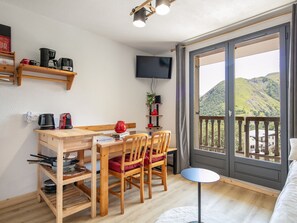 A cozy room with a wooden desk, chairs, a small table, a TV, and a balcony with a mountain view. - Studio with a balcony and a view of the mountains (Saint-Sorlin-d´Arves)