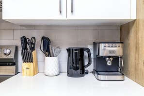 Eine Küche mit Kaffeemaschine, Messern und einem Schneebesenhalter.