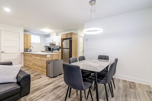Eine moderne Küche mit Kochinsel, Esstisch mit Stühlen und einer Couch.