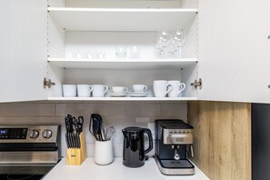 Eine Küche mit weißen Schränken, einer Kaffeemaschine und verschiedenen Küchenutensilien.