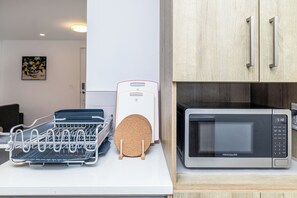 Une cuisine équipée d’un four à micro-ondes, d’un égouttoir à vaisselle et d’un tableau blanc.