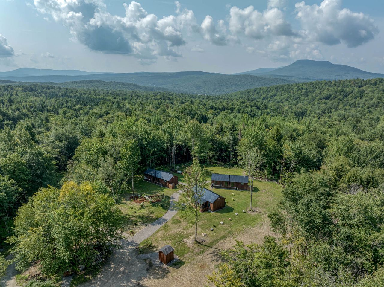 A forested area with a cabin and a barn.