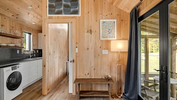 A wooden interior with a kitchen, a bench, a table, and a view through a glass door.