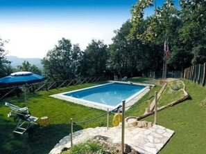 A rectangular swimming pool surrounded by a grassy area, with a flagpole and a covered seating area. - Le Piane by Interhome (Lucca)