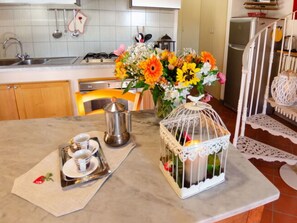 A kitchen with a coffee maker, a tray with cups, a vase with flowers, and a birdcage. - Le Piane by Interhome (Lucca)