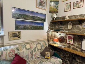 A room with a patterned sofa, a stone wall, and various framed pictures. - Le Piane by Interhome (Lucca)