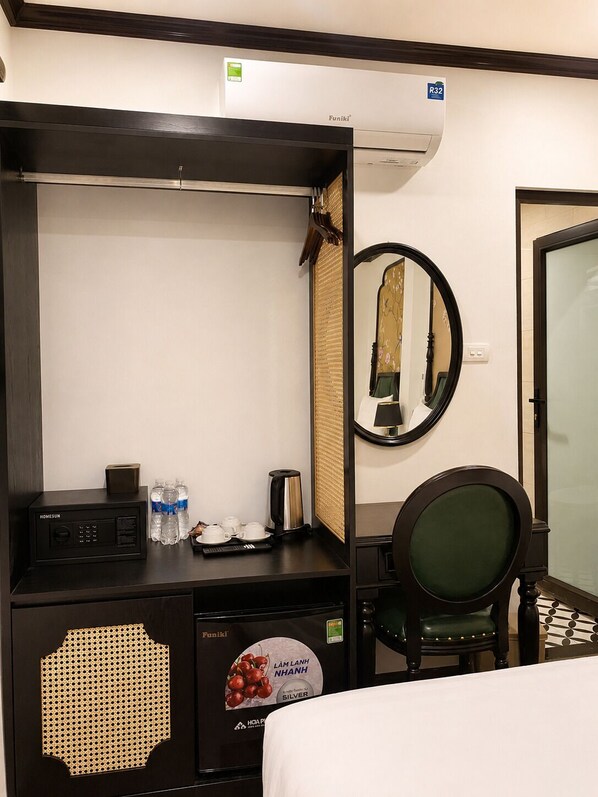 A hotel room with a bed, a desk with a coffee maker, a mirror, and a wall-mounted air conditioner. - Hanoi Silk Crown  Boutique Hotel & Spa  (Hanoi)