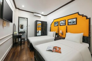 Habitación de hotel con dos camas, un escritorio, una silla, un televisor y un espejo.