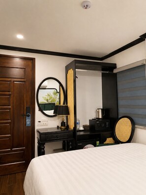 Habitación de hotel con cama, escritorio, espejo, ventana con persianas y puerta.