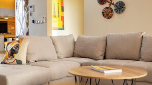 Ein modernes Wohnzimmer mit einem Ecksofa, einem runden Holztisch und dekorativer Wandgestaltung.