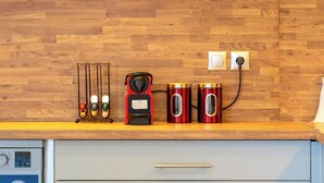Eine Küche mit Holzrückwand, einer Kaffeemaschine, zwei roten Behältern und einer Uhr.