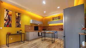 Eine moderne Küche mit Holzboden, einer zentralen Kochinsel und einem grauen Kühlschrank.