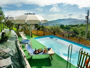 Uma piscina com escorregador, cadeiras de descanso e guarda-sol.