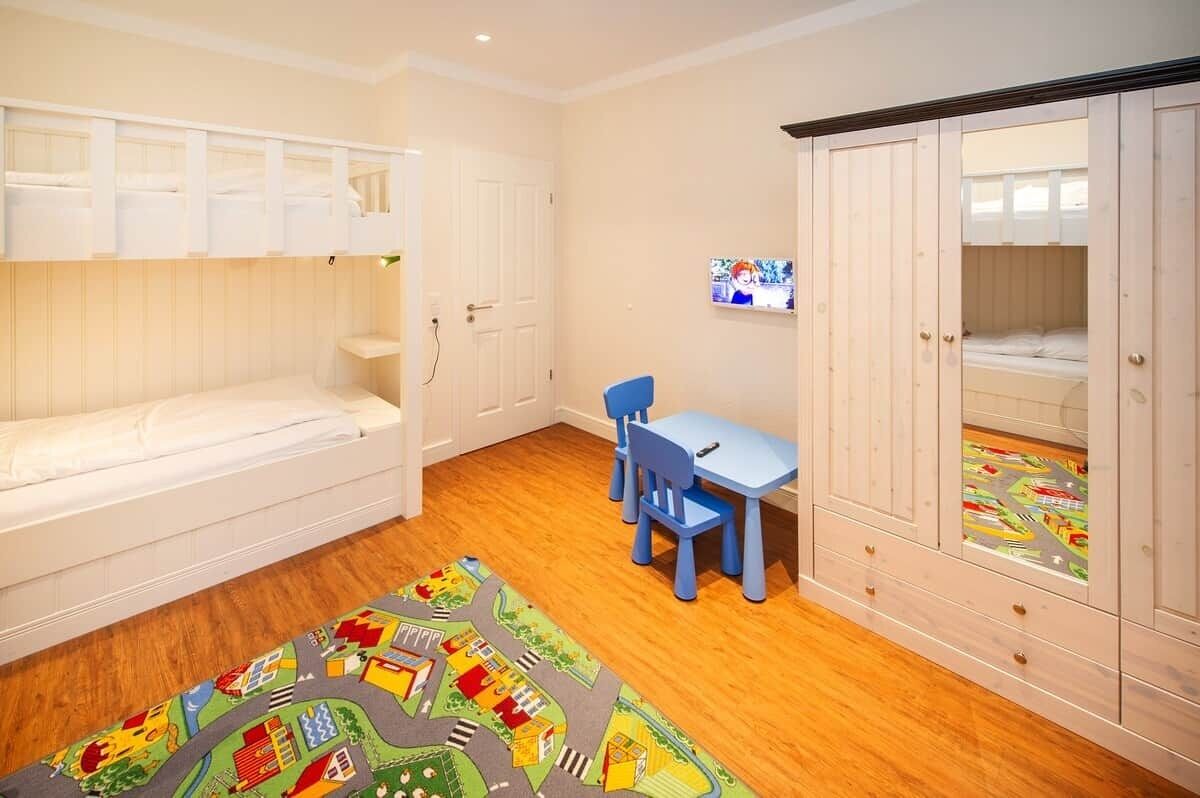 Een kinderkamer met stapelbedden, een bureau en een kledingkast.