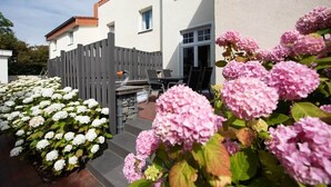 A residential building with a patio area, outdoor seating, and a wooden fence. - Feuerstein Family Home, Apartment 4 (Wangerooge)