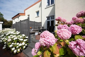 A residential building with a patio area, outdoor seating, and a wooden fence. - Feuerstein Family Home, Apartment 4 (Wangerooge)