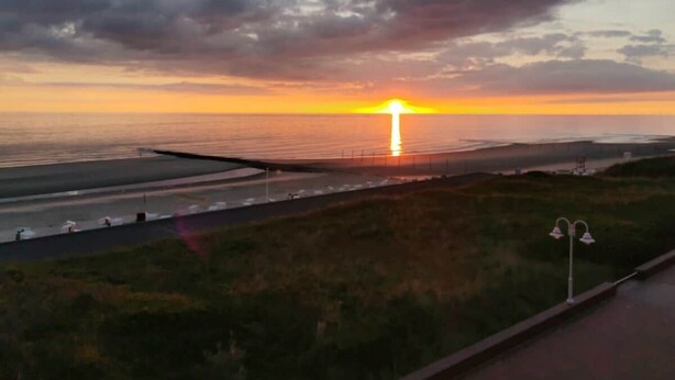 A sunset over a coastal area with a road and a grassy embankment. - Feuerstein Family Home, Apartment 4 (Wangerooge)