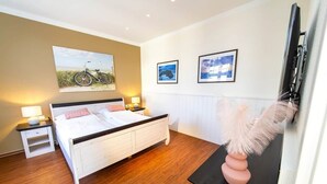 Une chambre à coucher avec un lit, des tables de chevet, une lampe et des œuvres d’art murales.