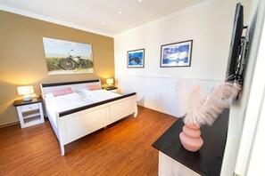 Ein Schlafzimmer mit einem Bett, Nachttischen, einer Lampe und Wandbildern.
