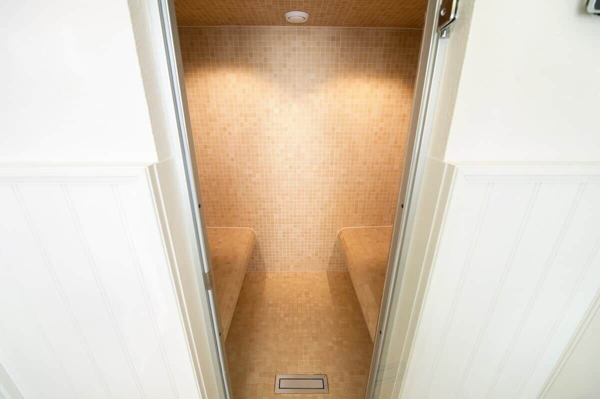 A narrow, tiled shower area with a drain at the bottom.