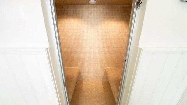 Un petit espace de douche, carrelé, avec un drain situé au fond.