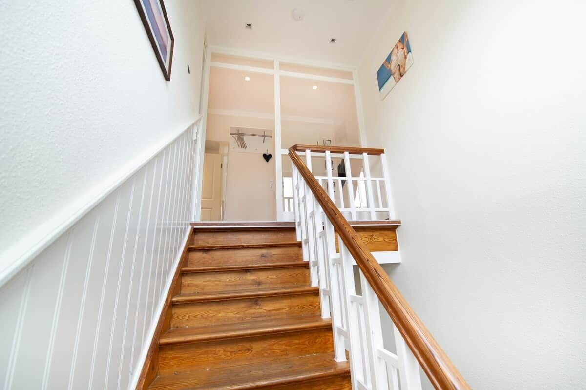 A wooden staircase with white railings leading to a door.