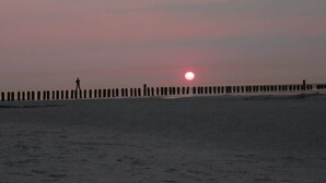 A beach with a person walking along a wooden pier. - Feuerstein Family Home, Apartment 5 (Wangerooge)