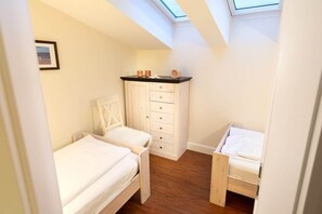 A bedroom with a skylight, a bed, a dresser, and a chair. - Feuerstein Family Home, Apartment 5 (Wangerooge)