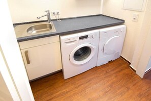 Eine kompakte Küche mit Spüle, Arbeitsplatte und einer Waschmaschine mit Frontlader.