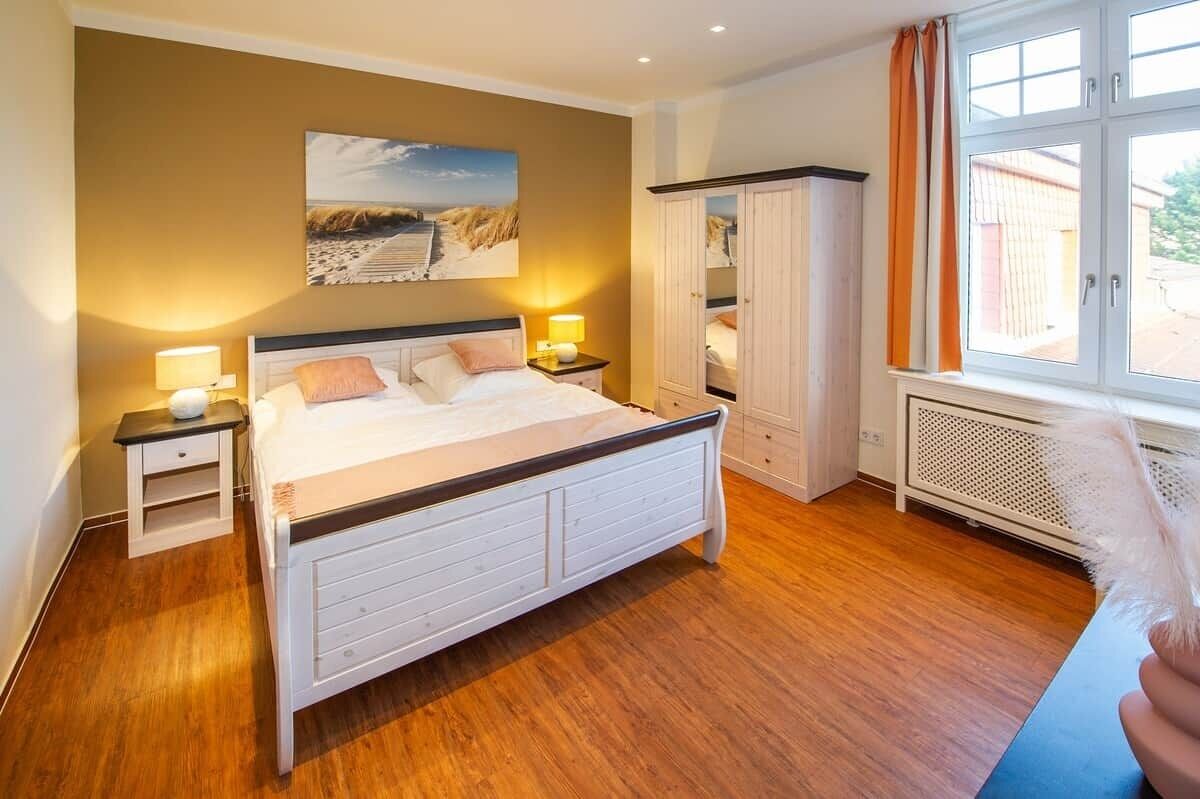 Een slaapkamer met een bed, nachtkastjes, een kledingkast en een raam.
