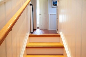 Eine Holztreppe mit weißen Wänden und einer Tür oben.