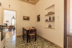 A dining area with a table and chairs, a chandelier, and a cross on the wall. - La Finestra sul Blu (Favignana)