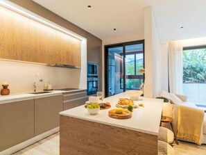 A modern kitchen with wooden cabinets, a central island with food items, and a view of the outdoors through a glass door. - All you need Apartment City Center by Interhome (Funchal (Madeira))