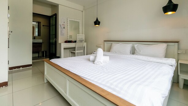 Ein Hotelzimmer mit einem großen Bett, einem Schreibtisch, einem Sessel, einem Spiegel und einer Pendelleuchte.