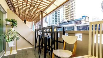A covered outdoor seating area with a wooden ceiling, a potted plant, and a chair.