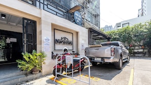 Ein Gebäude mit einem Schild für 'Narastay' und einem Verbotsschild für Parken. Ein Motorrad ist vor dem Gebäude abgestellt, und ein Pritschenwagen steht rechts daneben.