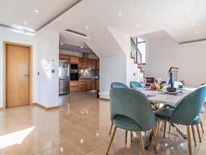 A modern kitchen with a dining area, a staircase, and a door leading to another room. - Camara de Lobos Lux by Interhome (Câmara de Lobos (Madeira))