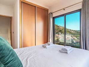 Ein Hotelzimmer mit Bett, Blick auf eine Hügellandschaft und einer Schiebetür.