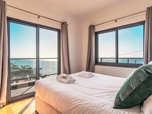 A hotel room with a bed, two windows, and a view of the sea. - Camara de Lobos Lux by Interhome (Câmara de Lobos (Madeira))