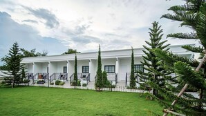 A white building with a covered porch and a well-maintained lawn. - Inter Paradise Resort (Dan Khun Thot)