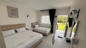 A hotel room with two beds, a desk, a mirror, and a window with curtains. - Inter Paradise Resort (Dan Khun Thot)