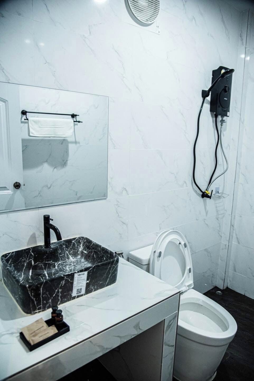 A bathroom with a marble sink, toilet, and a towel rack.