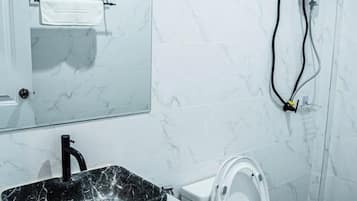 A bathroom with a marble sink, toilet, and a towel rack.